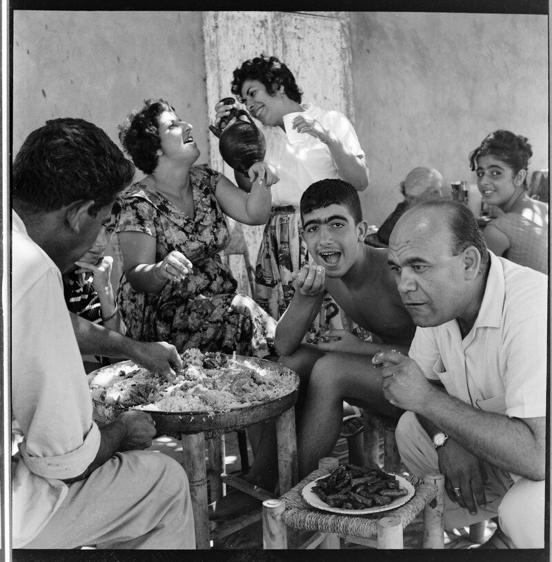 صورة عتيقة لعائلة جغليان تأكل الفتة في غزة ، وهو طبق نموذجي يؤكل في جميع أنحاء العالم العربي مع مكونات تختلف إقليميا (الصورة Kegham Djeghalian ، أقصى اليمين).