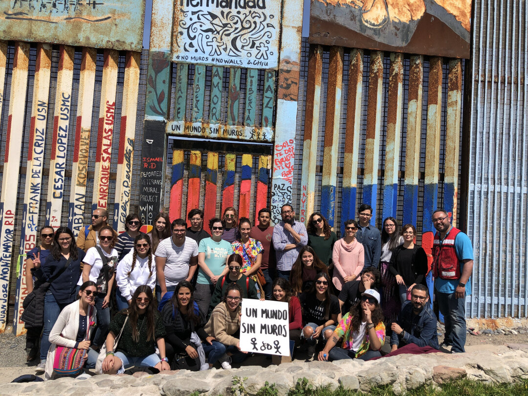 El artista mexicano Enrique Chiu (extrema derecha) con voluntarios, pinta muros fronterizos y aboga por una 