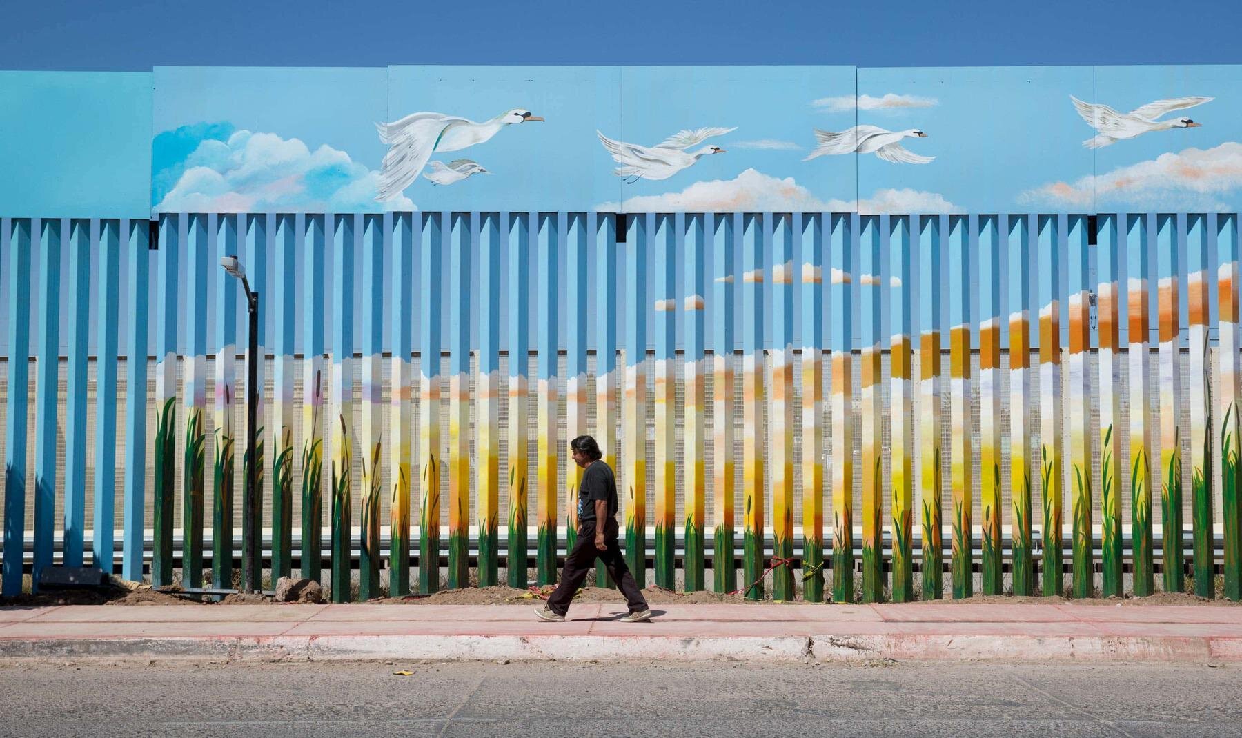 Artistas mexicanos pintan el muro fronterizo con Estados Unidos para hacerlo desaparecer.