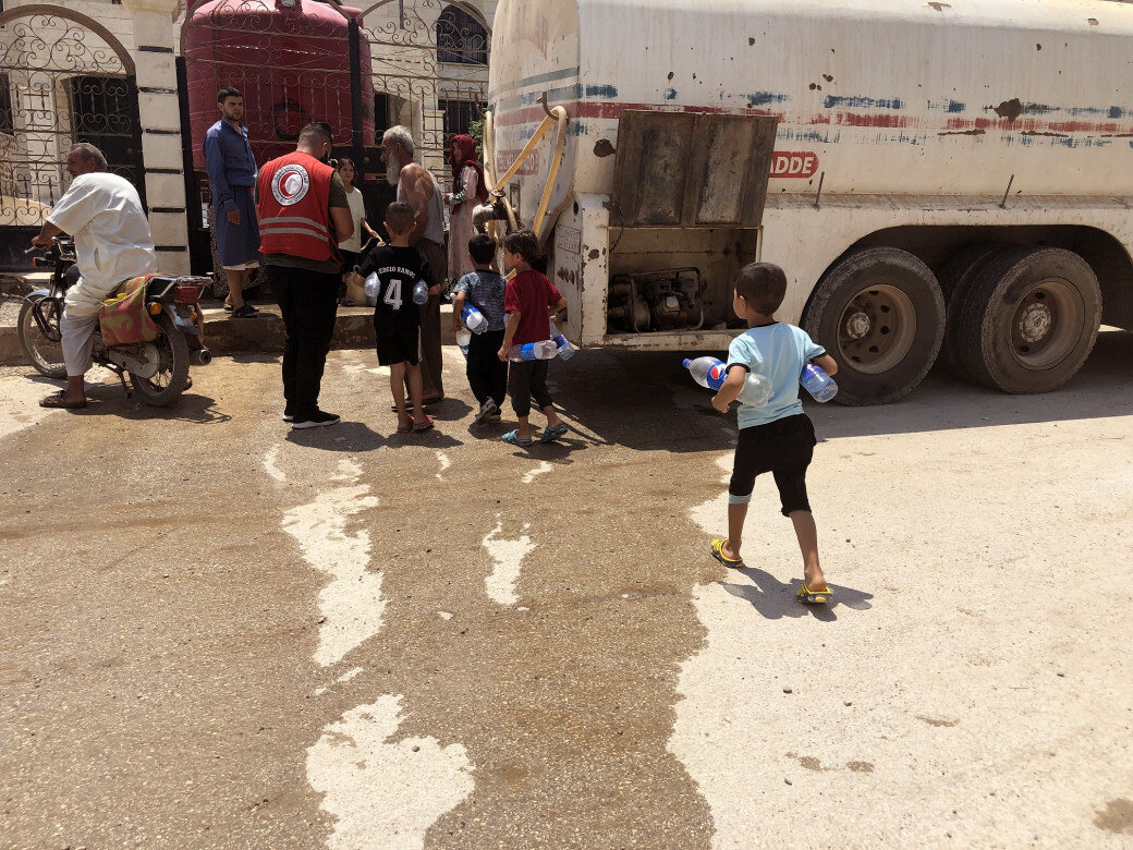 وبدلا من حمل الألعاب أو الكتب المدرسية، يحمل الأطفال في الحسكة زجاجات وحاويات المياه الثقيلة (الصورة: اللجنة الدولية للصليب الأحمر).