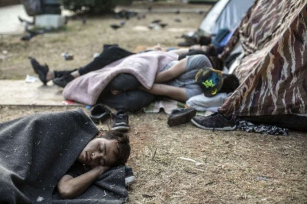 Des migrants afghans dorment à même le sol dans un camp de fortune situé dans le Pedion tou Areos (Champ-de-Mars), dans le centre d'Athènes, après avoir passé la nuit à Athènes en provenance des îles de l'est de la mer Égée.