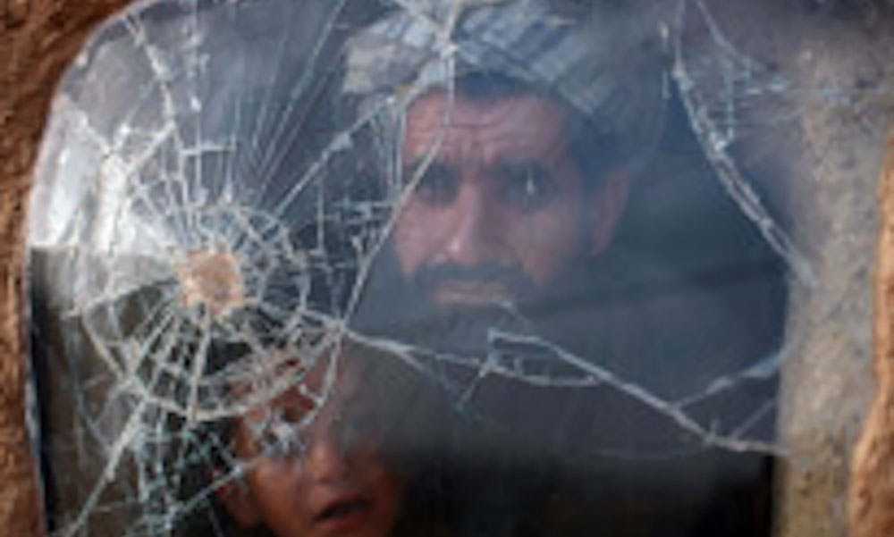  Internally-displaced Pashtuns from southern Afghanistan look through a car windscreen refashioned as a window in a windswept mudhut dwelling in a camp close to the Afghan city of Herat.