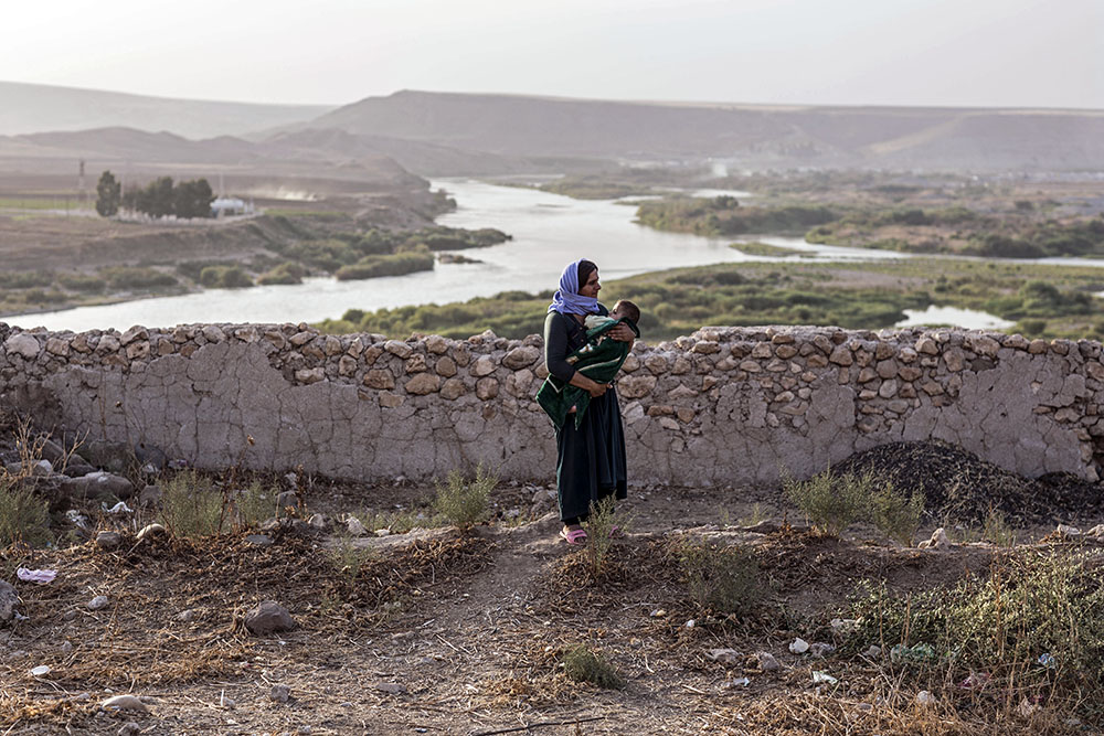 Dans le nord de l'Irak, une femme porte son enfant avec, en toile de fond, le fleuve Tigre, où la Syrie et la Turquie se rejoignent.