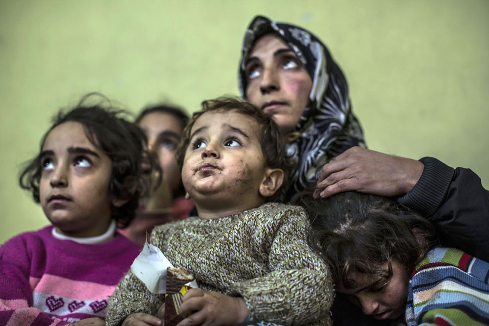 Contrainte par les circonstances, une famille syrienne du sud de la Turquie vit dans une pièce enfumée et à peine chauffée, couchée sur des couvertures sales. Ses membres connaissent des épisodes de dépression débilitante. Des enfants suivent des cours dans une école de l'Unicef dans le camp d'Eslahiye, dans le sud de la Turquie.