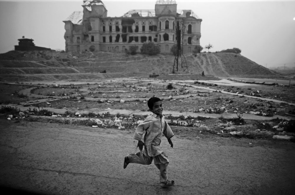 A young Afghan boy runs past the crumbling neoclassical edifice of Darulaman Palace in Kabul. The historical building, constructed in the 1930s, is the former palace of Afghan King Zahir Shah and also served as the Ministry of Defence.