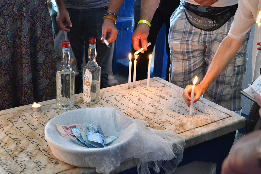 12-13. Pilgrims positing boukha bottles, dinar bills and lighting candles on the tomb of the venerated Rabbi Yacoub Slama.