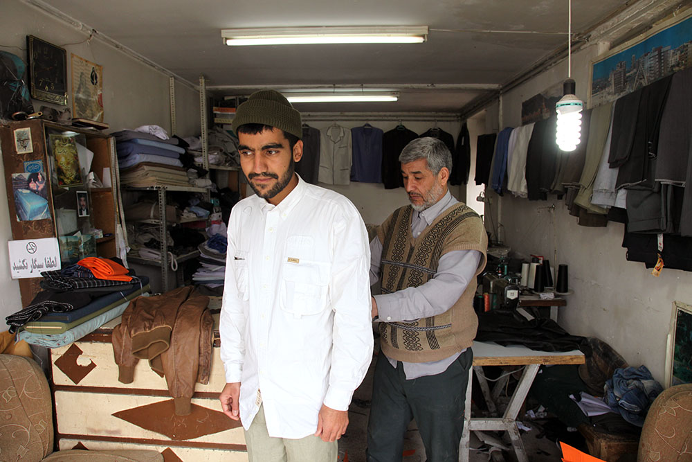 This tailor, who only sews clerical outfits, takes the measurements of a young cleric in Mashhad.  