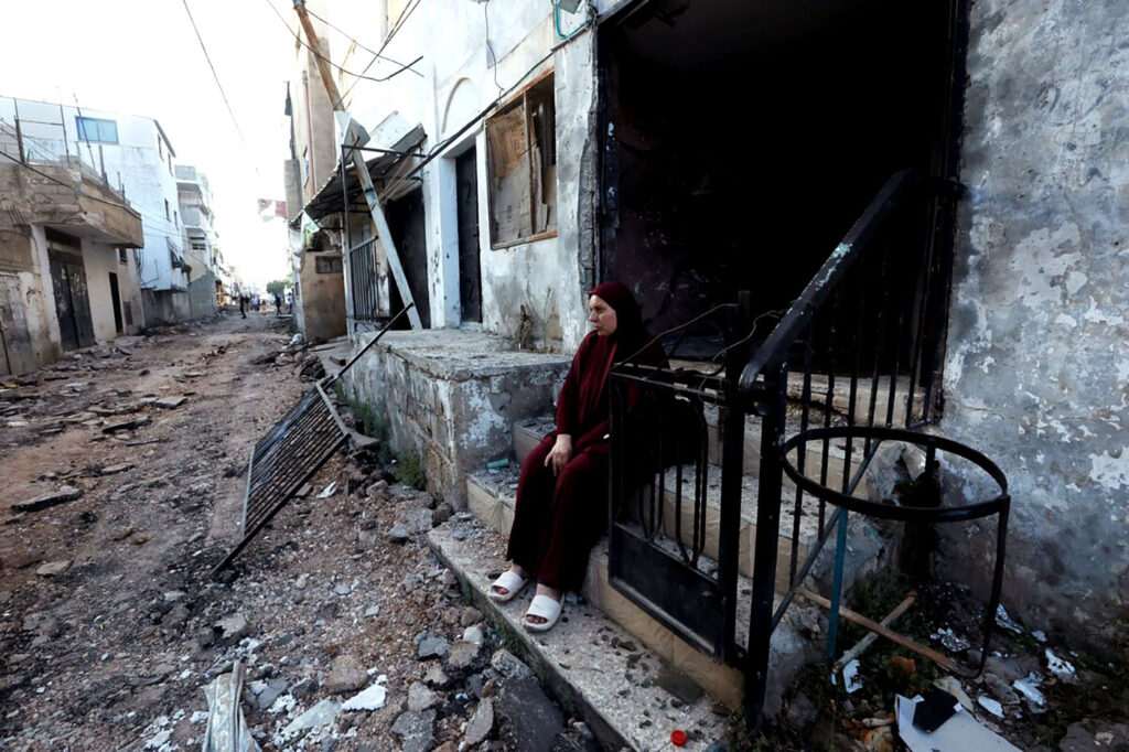 A Palestinian woman sits in front of a damaged building after the Israeli army's withdrawal from the Jenin camp in the Israeli-occupied West Bank on Wednesday.