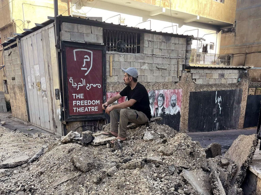 a man sits on rubble in July 2023 near the freedom theatre in jenin
