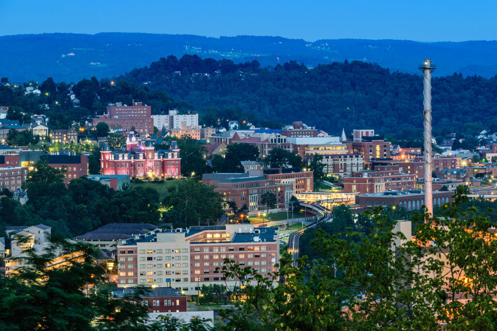 The campus of West Virginia University, known as WVU, and downtown Morgantown, West Virginia from above at dusk courtesy Simathers