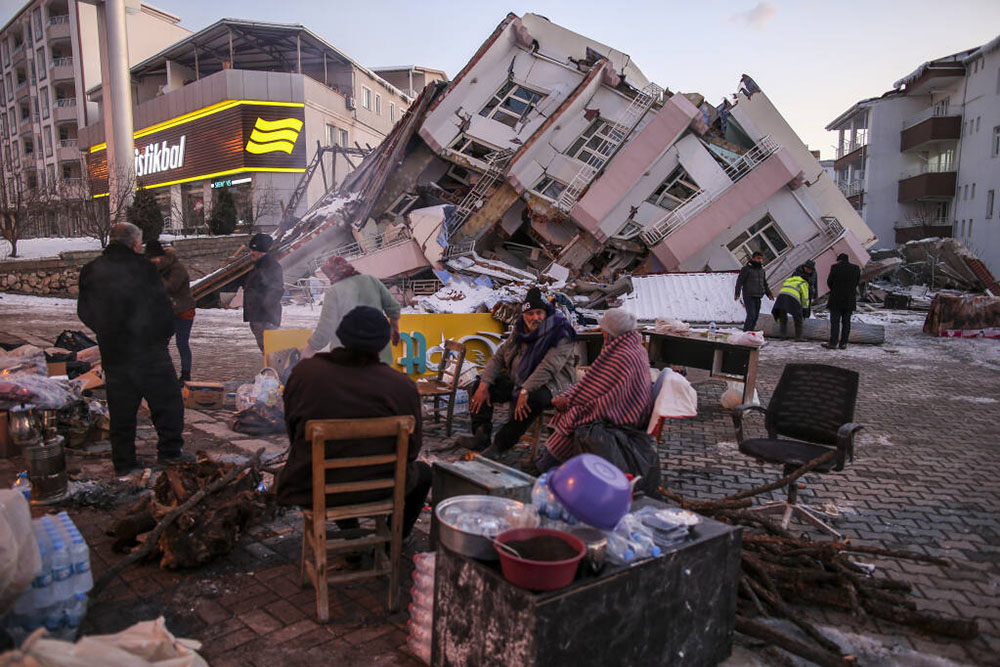 People sit and stand around collapsed buildings in Golbasi, in Adiyaman province, southern Turkey, after the 7.8 earthquake (photo Emrah Gurel).