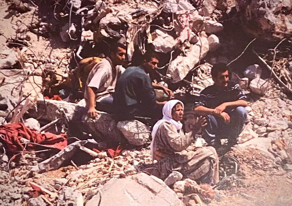 A family in the rubble of their home, Jenin Refugee Camp, 2002 - photo Jennifer Lowenstein