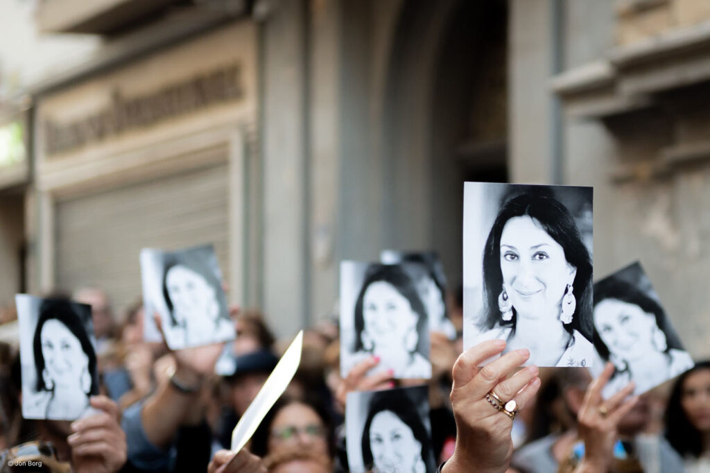 People hold up photos of Daphne at a protest on the first anniversary of her assassination, in Valletta Malta. Photo by Jon Borg