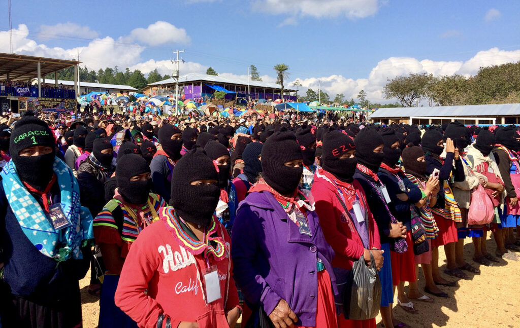 Zapatista women and Zapatista women and thousands of women from around the world listen to the opening address kicking off the first International Political, Artistic, Sporting, and Cultural Gathering of Women who Struggle in the Zapatista Caracol in the Tzots Choj region, Chiapas, Mexico, March 8, 2018. Photo by Heather Gies