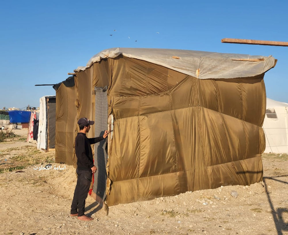 Palestinian man making a tent out of parachutes used to drop aid on the Gaza Strip, 2024 (photo Osama Kahlout).