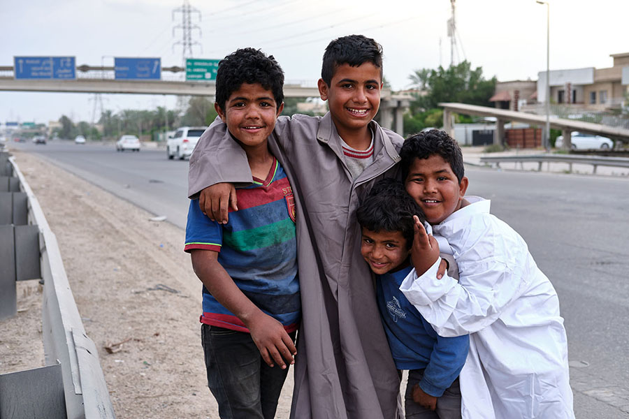Nabil Salih Abdul-Qayoum (left) and his comrades pose for the camera on their way home. They were selling chewing gum to the few drivers during a coronavirus lockdown in the western part of the capital. Baghdad, April 2020.