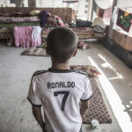 Displaced boy with his family from the Iraqi city of Mosul, following its takeover by Islamic state, in a half-built apartment complex occupied by thousands of refugees, in the northern Iraqi town of Zakho, 2014. Photograph by Iason Athanasiadis.