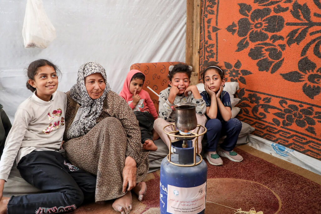 A family displaced by the war in Gaza, sits in their tent with a new portable gas stove provided by MCC partner, Al-Najd Developmental Forum staff.