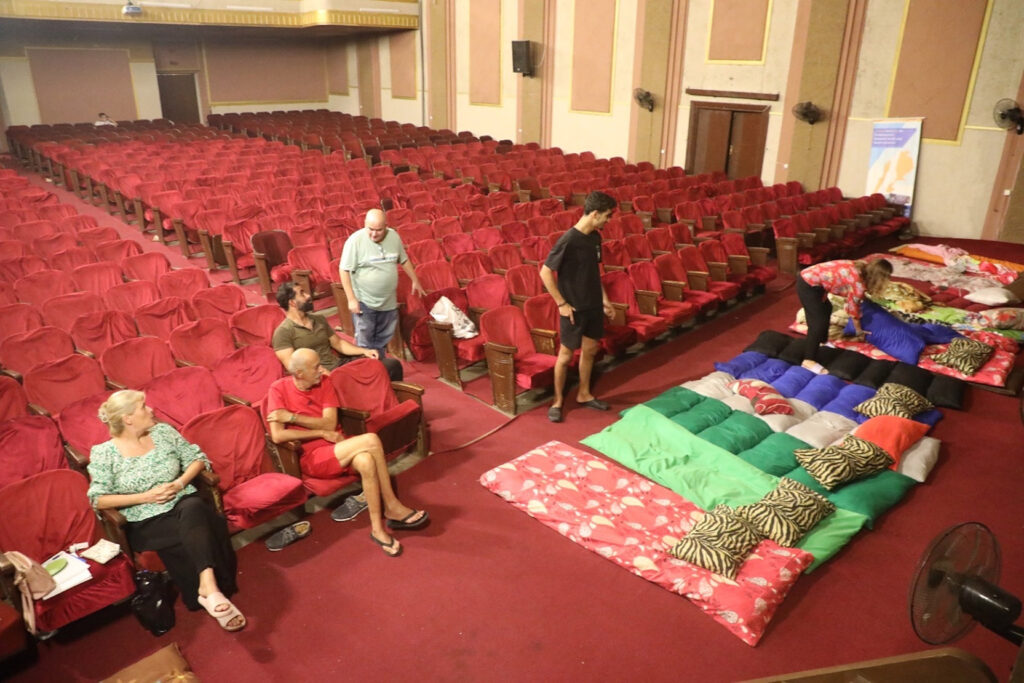 A displaced family prepares to bed down in the theatre of one of Tiro’s three cultural centers across Lebanon, March 2016. (Courtesy Qassem Istanbouli)
