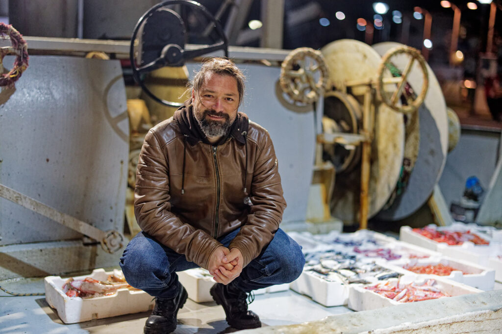 Trawler captain Thanasis Ladopoulos poses among his catch aboard his boat on the port of Limnos