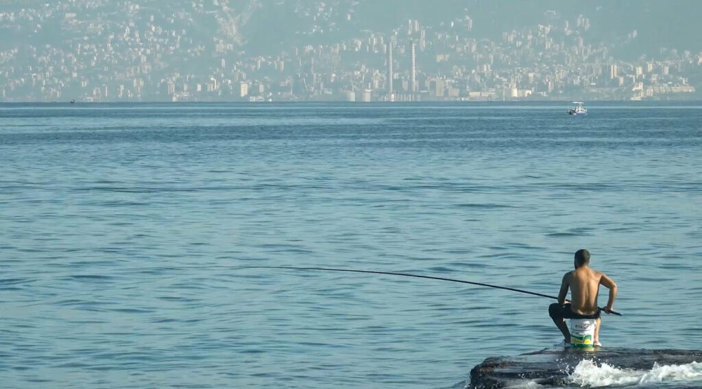 A fisherman at the Beirut corniche. Still from And the Fish Fly Above our Heads.